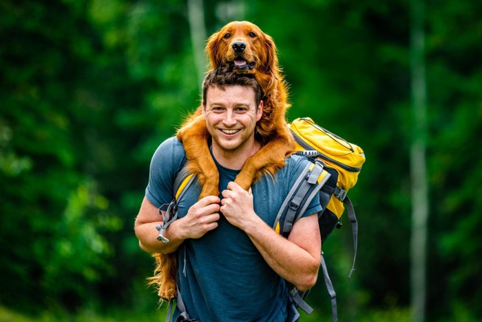 男性とおんぶされた犬